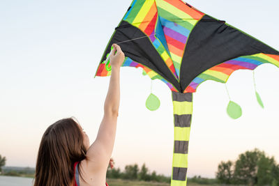 Rear view of woman holding umbrella against sky