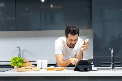 Young man holding ice cream in kitchen