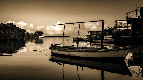 Sailboats moored on lake against sky during sunset