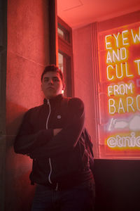 Portrait of young man standing by red wall