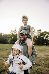 Happy boys having fun with male camp counselor in playground