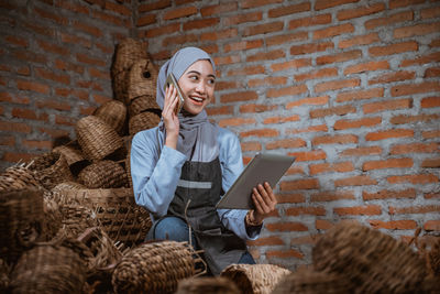 Low angle view of young woman sitting against wall