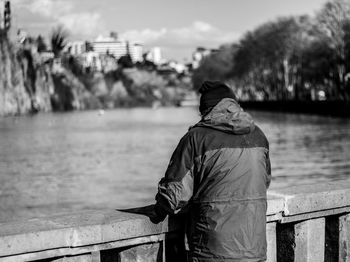 Rear view of woman wearing warm clothing while standing by river