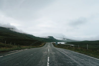 Empty road by mountain against sky