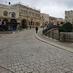 People on street amidst buildings in city against sky