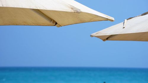 Two beach umbrellas close up by sea and sky