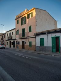 Empty road by buildings against sky in city