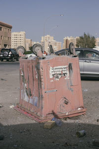 Information sign on road in city against sky