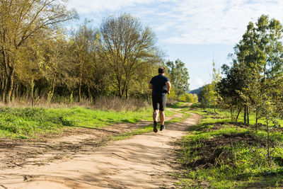 Rear view of man walking on dirt road