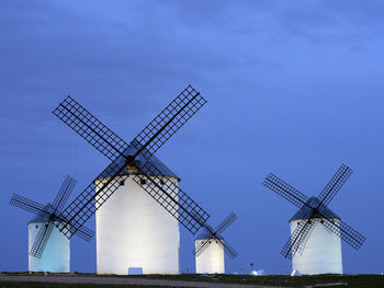 Traditional windmill on field against blue sky