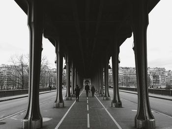 Rear view of people walking under bridge