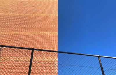 Low angle view of fence against clear blue sky