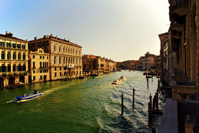 Canal amidst buildings in city against sky