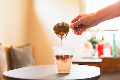 Cropped hand pouring water in glass on table