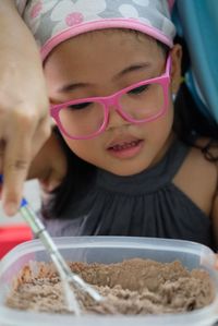 Close-up of hand helping girl preparing food on table