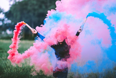 Young woman holding distress flare on field