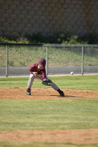 Little league baseball boy missing a ground ball on the infield