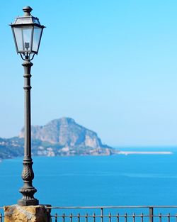 Street light by sea against clear sky