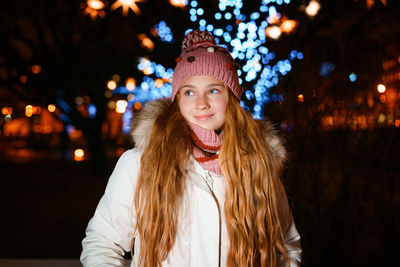 Blonde teenager with long hair in winter clothes on festive winter evening