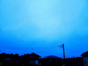 Low angle view of silhouette buildings against blue sky