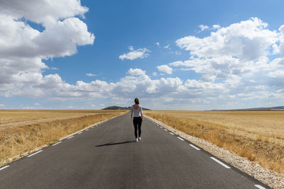 Rear view of woman walking on road against sky