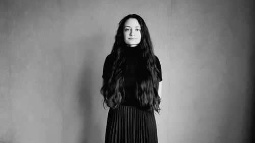 Portrait of young woman standing against wall