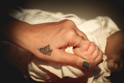 Close-up of woman hand with tattoo on bed