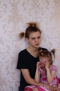 Portrait of a girl sitting against wall