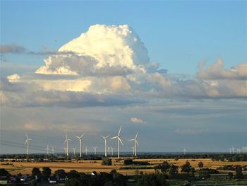 Windmills on field against sky