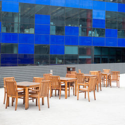 Empty chairs and tables against building