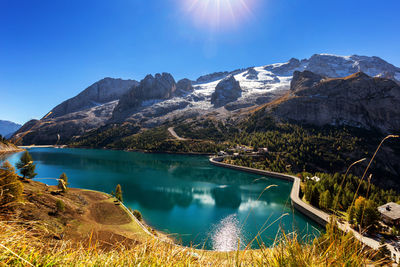 Scenic view of lake by mountains against blue sky