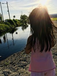 Rear view of woman standing by lake against sky