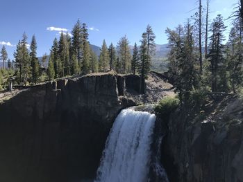 Scenic view of waterfall in forest against sky