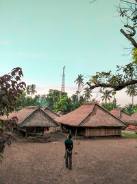 Rear view of man outside house against sky