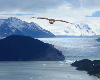 Scenic view of sea by snowcapped mountains against sky