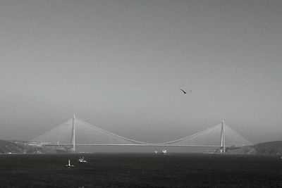 Suspension bridge over city against sky