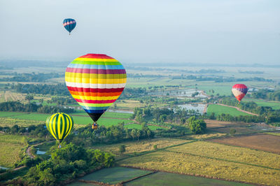 Hot air balloon flying over field against sky