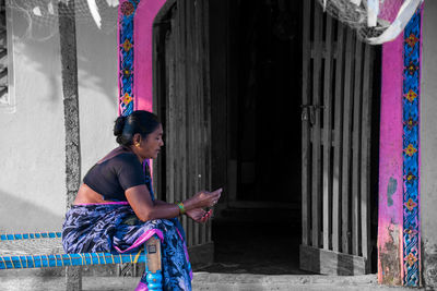 Full length of woman sitting on multi colored building