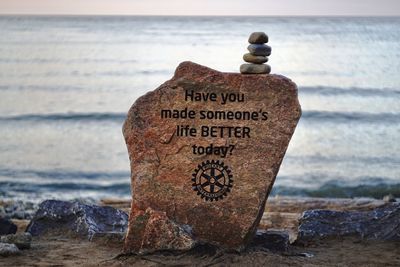 Text on rock at beach against sky