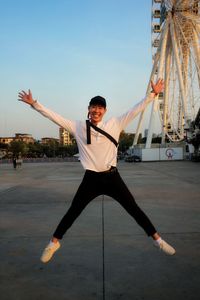 Man with arms outstretched against sky