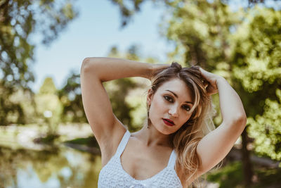 Portrait of beautiful young woman against tree