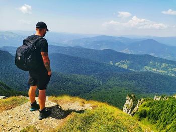 Rear view of man looking at mountains against sky