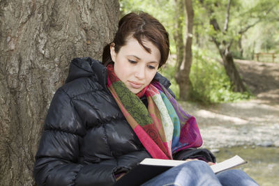 Mid adult woman sitting on tree trunk