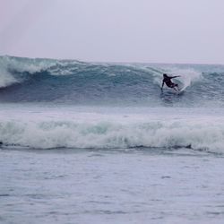 Man surfing in sea against sky