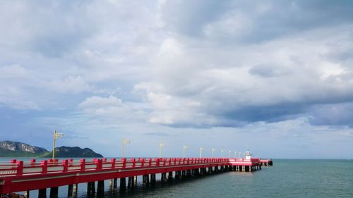 Bridge over sea against cloudy sky