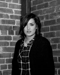 Portrait of young woman standing against brick wall