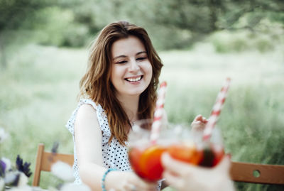 Young woman smiling while holding glass outdoors