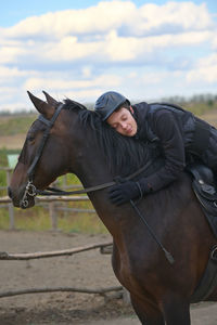 Boy sleeping while sitting on horse against sky