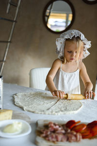 Little girl cooking pizza in the kitchen