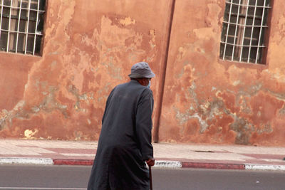 Rear view of man walking on street against building